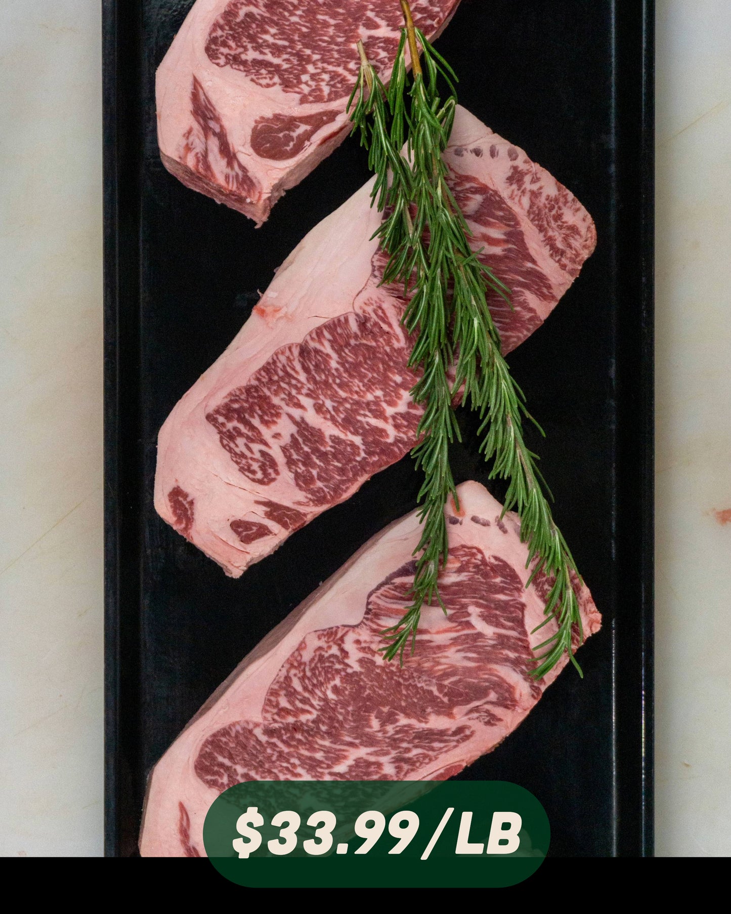 New York Strip Steaks on a black tray with price label $33.99/lb